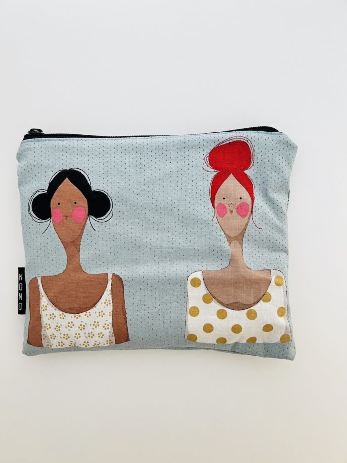 Pussukka, jonka kankaassa kaksi naista. Toisella punaiset hiukset ja toisella tummat.