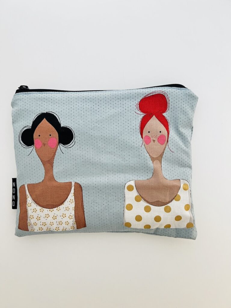 Pussukka, jonka kankaassa kaksi naista. Toisella punaiset hiukset ja toisella tummat.